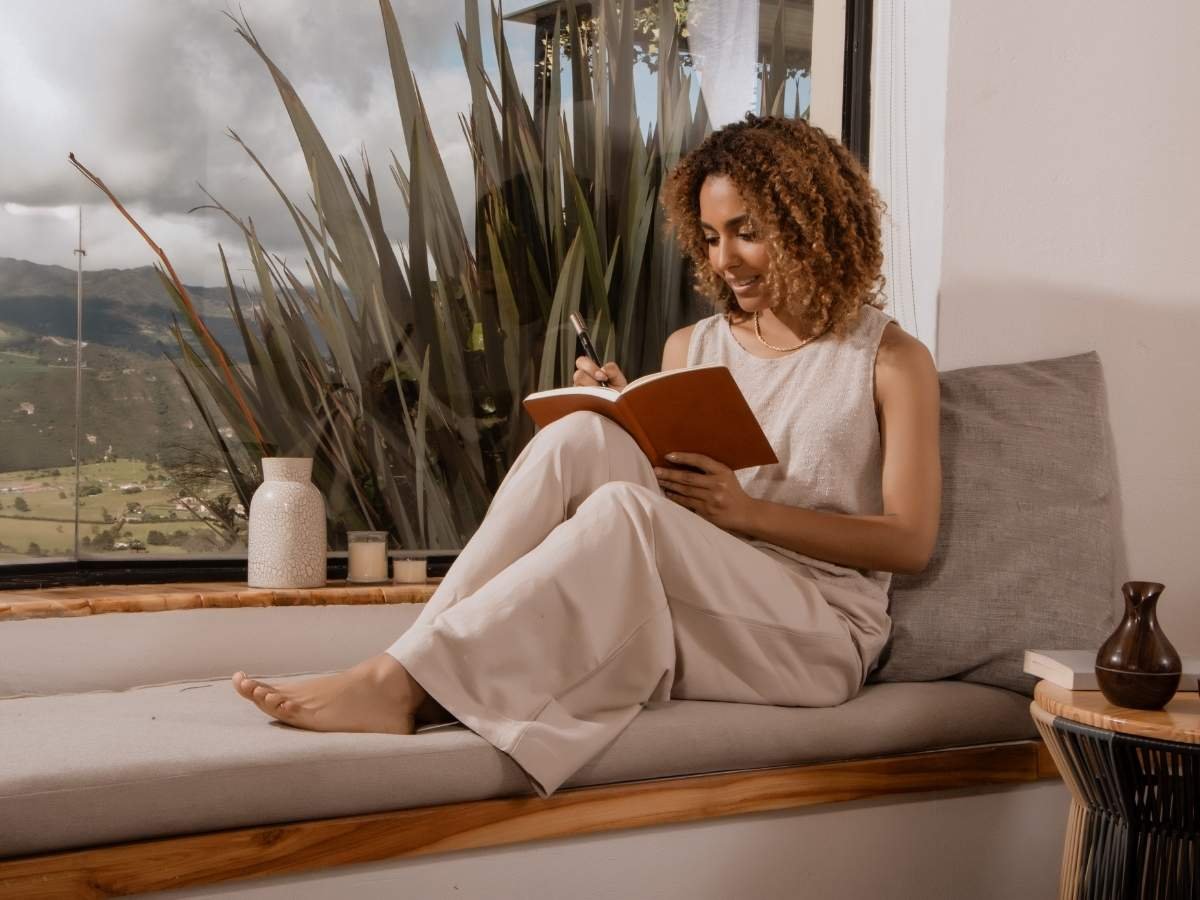 a girl with a morning coffee and journal by a window, representing a calm daily routine for managing anxiety.