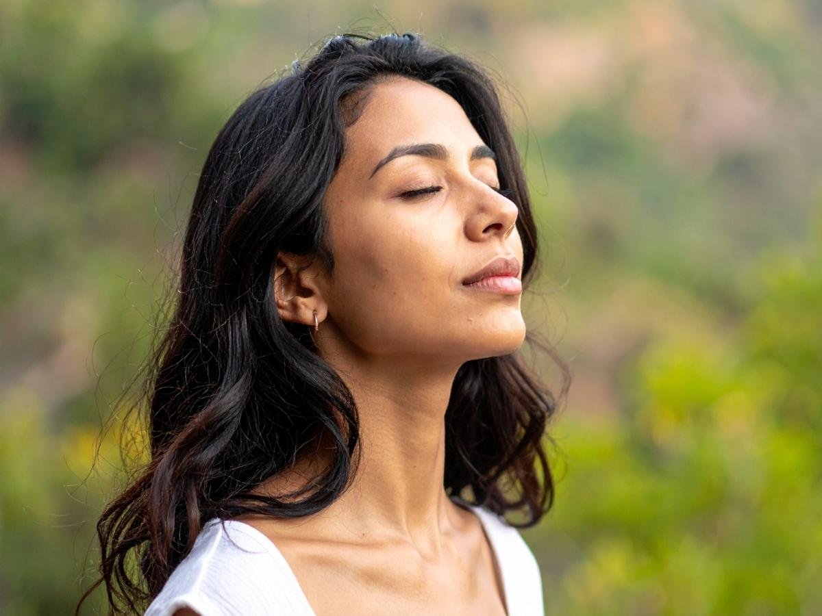 Girl standing calmly with eyes closed, representing the connection between mental anxiety and physical symptoms in the body