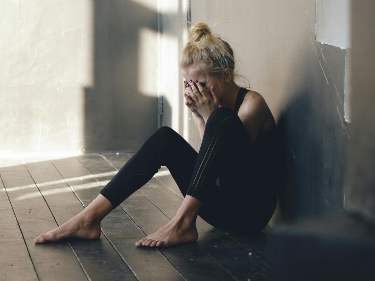 Person sitting alone quietly reflecting, representing the connection between burnout, anxiety and depression.