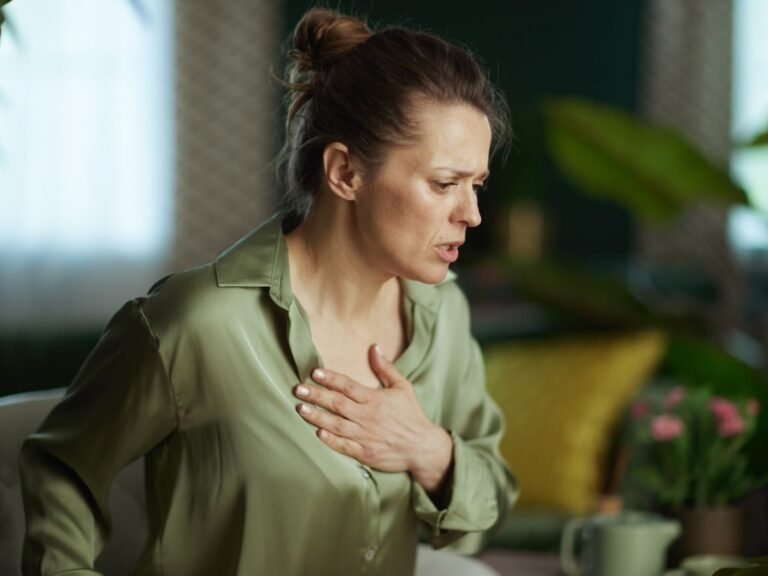 woman with hand on chest looking thoughtful, representing physical symptoms of anxiety that are often overlooked