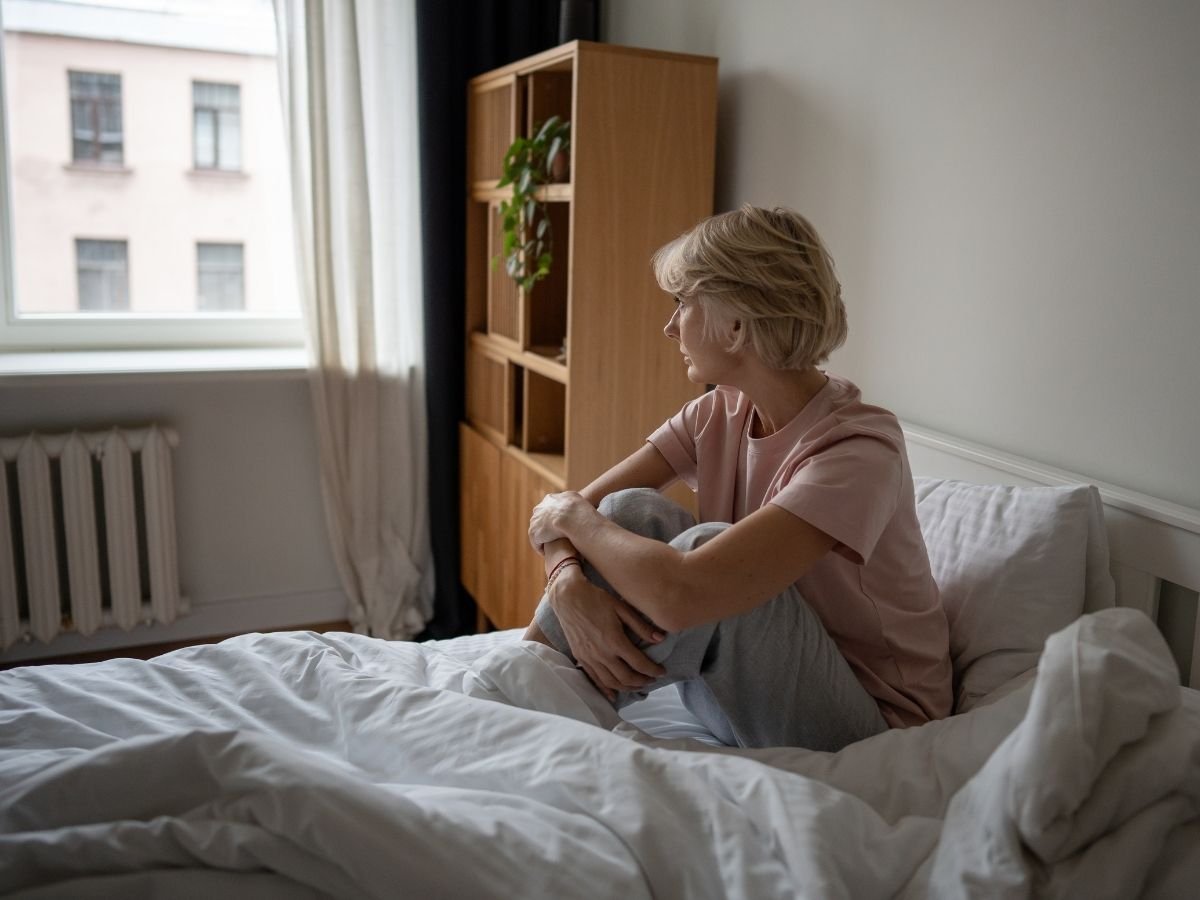 Person staring blankly out of a window looking disconnected, representing emotional detachment as a sign of burnout.