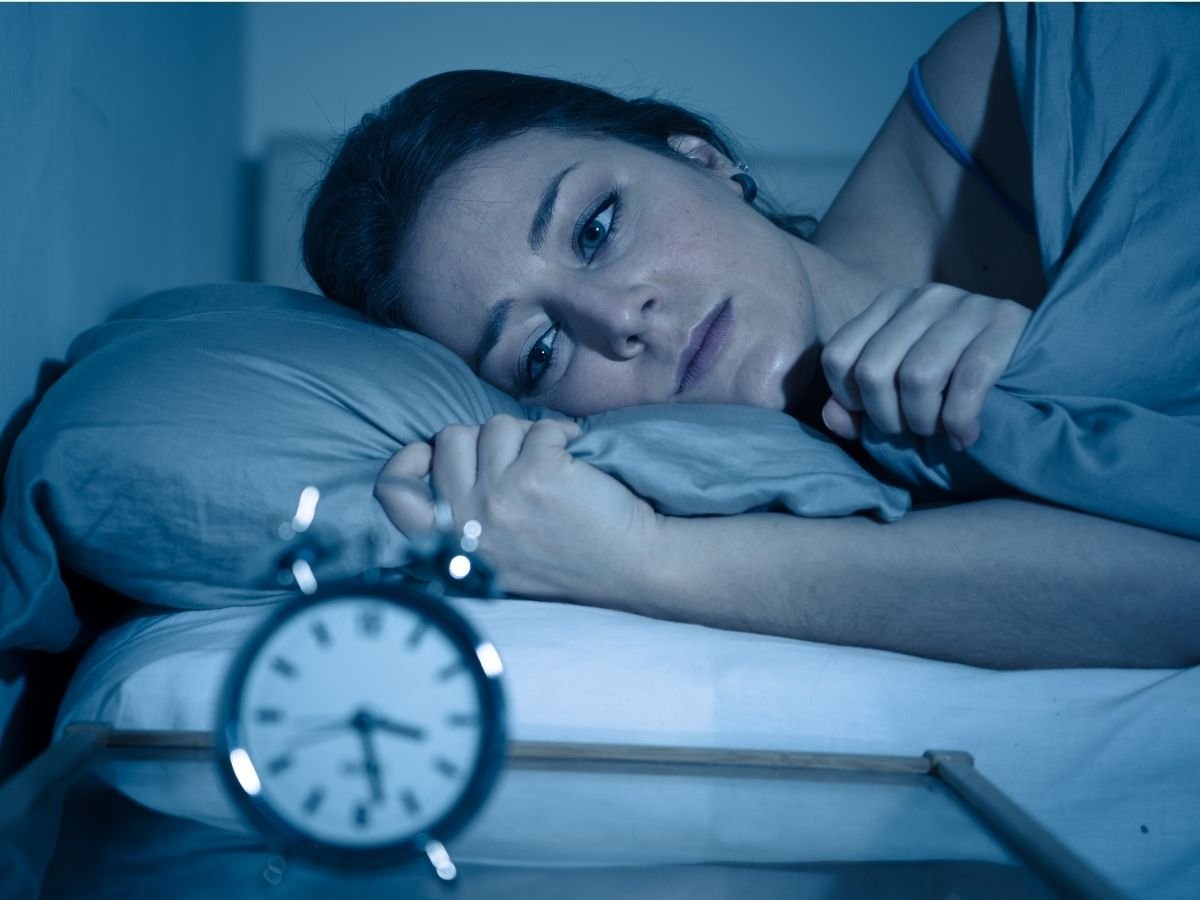 Person lying awake at night with worried expression, representing anxiety that persists without a clear cause.
