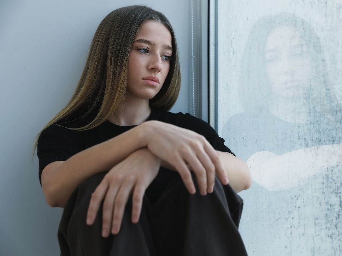 a sad or depressed girl sitting in front of window